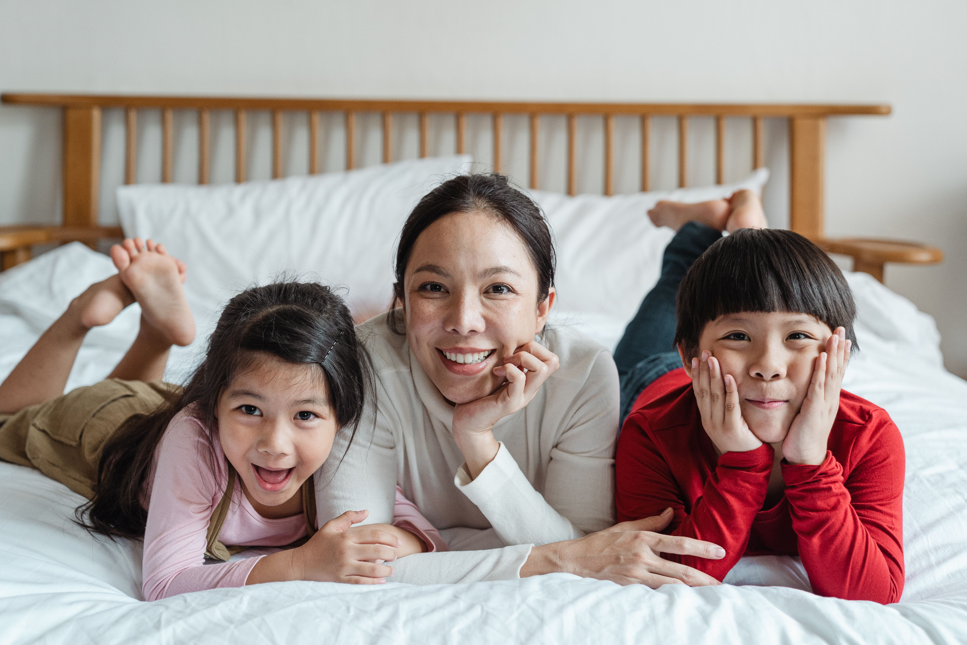 Mother and two children smiling together on a bed